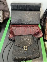 Four vintage ladies bags including two clutches with reptile texture, one shiny textured clutch, and one black glittery shoulder bag.