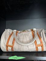 Front of cylindrical beige vintage handbag with brown trim and gold-tone hardware