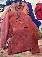 Four women's coats in various colors and fabrics, including a prominent textured red Loubin coat on top