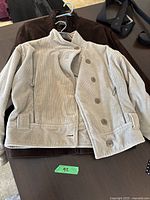 Two jackets laid flat on table, beige corduroy Armani jacket on top of brown suede Danier jacket.