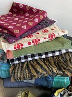 Stack of scarves in various colors and patterns showing geometric, floral, plaid and animal prints