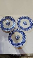 Three antique Flow Blue plates arranged on table showing overall design and condition.
