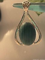 Close-up front view of large oval green gemstone pendant with sterling silver setting.