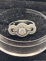 Front view of silver ring with central round clear Swarovski crystal and surrounding smaller crystals in a symmetrical loop design.