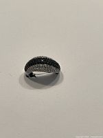 Front side view of a dome-shaped sterling silver ring with black and clear Swarovski crystals on top.