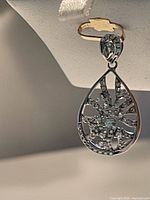 Close-up image of the front side of the silver pendant showing the floral/starburst crystal pattern.