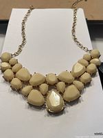 Full view of the antique style burlesque necklace showing the arrangement of cream-colored stones and gold-tone chain.