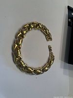 Gold plated bracelet shown from a slight angle revealing interlocking oval links and fold-over clasp.