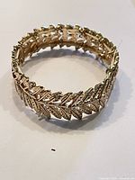 Gold plated bracelet laid flat showing the leaf link design from top view.