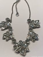 Full view of the silver-tone chain necklace with clusters of various shaped clear rhinestones, showing the overall design.