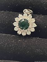 Front view of the Swarovski charm showing the green central crystal surrounded by clear crystals in a floral arrangement.