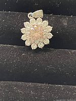 Close-up of the front side of the Swarovski crystal charm pendant showing the large, sparkly light pink center crystal and surrounding smaller clear crystals in a floral arrangement