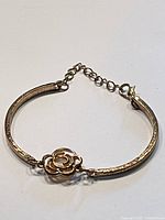 Full view of the vintage brass bracelet featuring a flower motif in the center with adjustable chain and lobster clasp.
