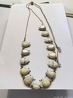 Full view of the vintage necklace laid flat showing all linked teardrop white stones on chain.