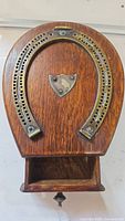 Front view of the vintage wooden cribbage board with metal horseshoe score track and small central shield emblem