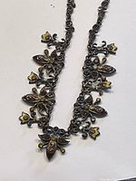 Close-up photo of the vintage rhinestone chain necklace showing floral and leaf shapes with yellow and clear rhinestones embedded.