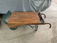 Side view of scale showing wooden platform, green wrought iron frame, cast iron wheel and curved wooden handles