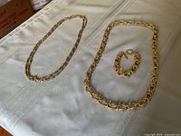 Wide view of all three jewelry pieces: a multi-strand chain necklace, large gold-tone chain necklace, and matching bracelet