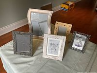 Full view of five photo frames arranged on floor, showcasing different styles and sizes.