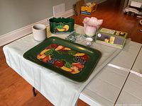 Overview of all items on table: metal tray with handpainted fruit, flower holder, three ceramic pots, glass beads, and candlemaking kit boxed set.