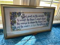 Full view of framed needlepoint Serenity Prayer showcasing the embroidered prayer text and floral border inside a gold antiqued frame.