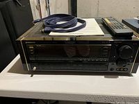 Front view of Pioneer Elite VSX-95 receiver with remote, cables and manual on top, showing buttons, display and knobs on receiver