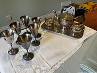 Set of six silverplate stemmed wine goblets next to tea set on tray