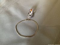Photo showing sterling silver snake motif ring with coral bead, and sterling silver bracelet arranged together on cloth surface.