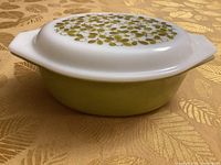 Photo showing side view of Pyrex casserole dish with green avocado glass base and white lid decorated with olive pattern.
