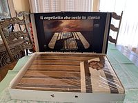 Original packaging box with vintage Italian velour bedspread inside wrapped in plastic with earth tone stripes visible.