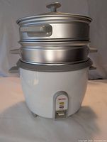 Front view of Aroma electric rice cooker with stacked steamer baskets and lid on top