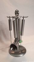 Front and side view of Bacardi stainless steel bar tool set with four tools (jigger, muddler, cutting utensil, stirrer) hanging neatly on holder stand with Bacardi logo