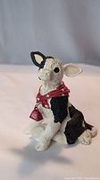 Front view of cow figurine with visible red bell and bandana