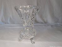 Front and side view of clear crystal vase showing detailed etched and hatched patterns and flared top with tripod feet base, placed upright