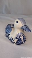 Front-side view of the ceramic duck figurine showing detailed blue handpainted patterns on white ceramic.