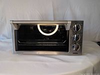 Front view of the Delonghi stainless steel convection toaster oven with glass door and control knobs on the right.