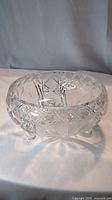 Front side view of clear crystal bowl showing geometric cut pattern and three knobbed feet.