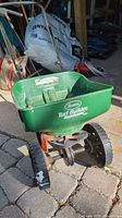 Full view of the green Scotts Turf Builder Seed Spreader showing two black wheels and hopper with label.