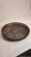 Photo of the tarnished silver platter showing round shape, pierced edge, and patina spots on surface.