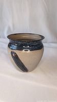Front side view of the studio pottery plant pot showing the beige textured body and blue-black glaze brushstroke.