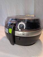 Front view of the TFAL Actifry air fryer showing handle and transparent lid.