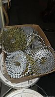 Box with multiple rolls of 3 inch galvanized steel framing coil nails, showing nail heads and arrangement in rolls.