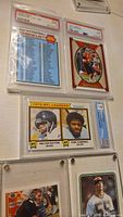 Photo showing four football cards in protective cases including Walter Payton, Earl Campbell, Brian Bosworth rookie, Brett Favre rookie, and Joe Burrow 2022 Legacy card.