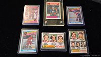 Six NHL hockey trading cards featuring Wayne Gretzky, Guy Lafleur, Steve Yzerman, and league leaders in goals, assists, and points. Cards vary in presentation, with one card encased in a plastic hard case and others in protective sleeves.