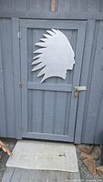 Front view of silver Indian Head silhouette wall decor mounted on a door for scale, showing feather headdress detail and smooth wooden finish.