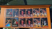 Photo showing a page of trading cards featuring Scottie Pippen and Shaquille O'Neal in various game action shots, protected in sleeves within an orange binder.