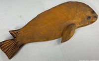 Top-down view of carved wooden harp seal figure on white background, showing the full length.