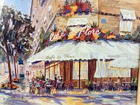 Close-up view of the print showing the cafe scene with tables and umbrellas outside on a street corner with a tree.