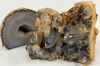 Front view of smoky quartz cluster with polished agate geode side showing in background.