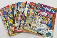 Eighteen vintage comic books fanned out, showing colorful covers featuring Jughead and other classic Archie characters in various seasonal and holiday themes.